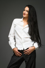 Young elegant business woman standing against grey background