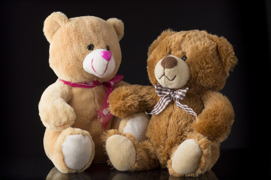 two toy teddy bears on a black background