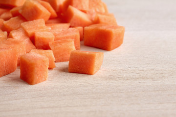 Diced raw carrots on a wooden chopping board