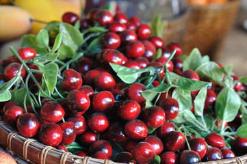 Many cherries in wooden basket, artificially