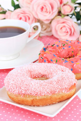 Sweet donuts with cup of tea on table close-up