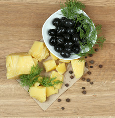 Parmesan cheese, fresh herbs and olives on wooden background
