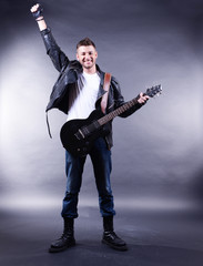 Fototapeta premium Young musician playing guitar on gray background