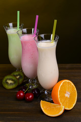 Milk shakes with fruits on table on dark yellow background