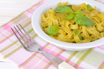 Delicious pasta with pesto on plate on table close-up