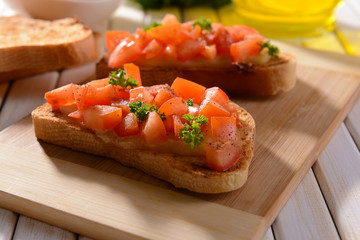 Delicious bruschetta with tomatoes on cutting board close-up