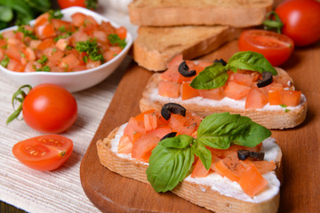 Delicious bruschetta with tomatoes on cutting board close-up