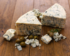 Tasty blue cheese with olives, on wooden table