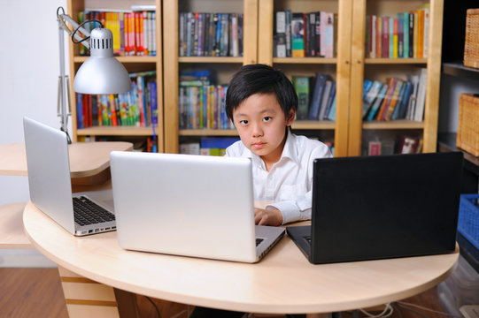Intelligent school child working on multiple laptop computers - Powered by Adobe