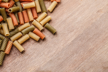 Multicolored pasta on wooden table with copyspace