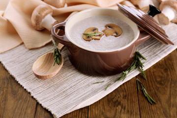 Mushroom soup in pot, on wooden background