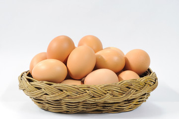 Many eggs in rattan basket on white table