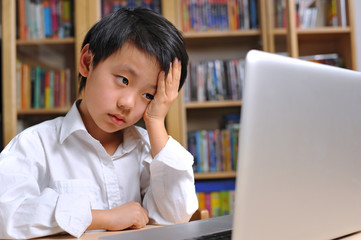 Asian school boy having headache working in front of computer