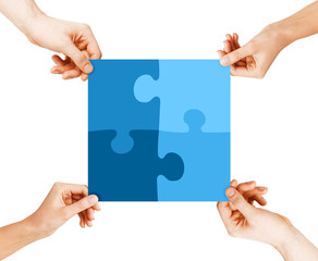 four hands connecting puzzle pieces
