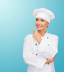 smiling female chef pointing finger to sonething