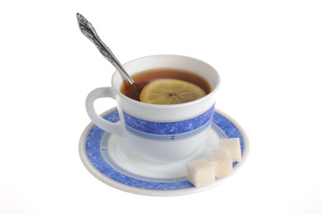 A cup of tea with one slice of lemon within and refined sugar on