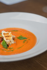 Image of tasty pumpkin soup with crouton and basil served in res