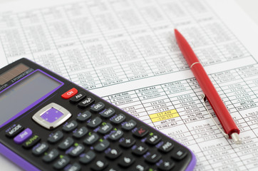 Calculator and pencil on the paper with financial data sheets