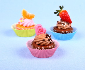 Three appetizing cupcakes with heart, tangerine, and strawberry