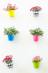 Plastic flower in vase on wall background