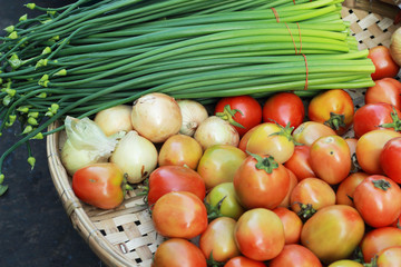 Fresh tomatoes with onion flowers on the market.