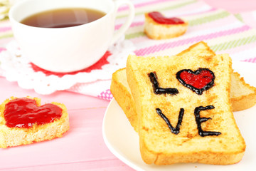 Delicious toast with jam and cup of tea on table close-up