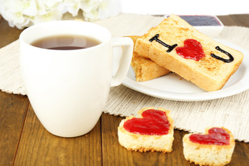 Delicious toast with jam and cup of tea on table close-up