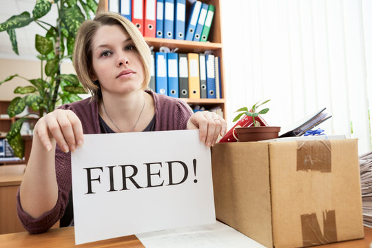Upset employee with collected things and paper with word "Fired"