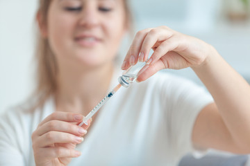 Closeup shot of young medical worker filling syringe with drug