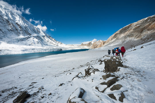 Trekkers walking in himalayas, with Tilicho lake on the left