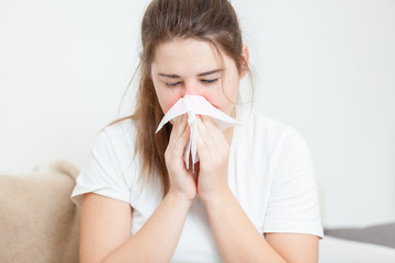 Closeup portrait of brunette woman sneezing in paper tissue