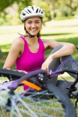 Happy woman wearing helmet with bicycle in park