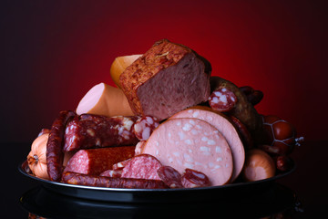 Lot of different sausages on salver on dark colorful background