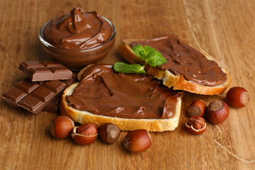 Bread with sweet chocolate hazelnut spread on wooden background
