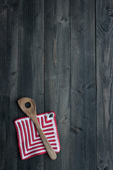 Fototapeta na wymiar Kitchen Utensils: Wooden Spoon and Potholder on Dark Wooden Back