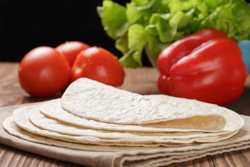 wheat tortillas with vegetables on old wooden table