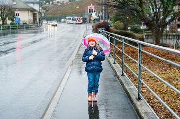 Cute little girl with umbrella in a city on a rainy day