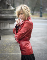 Pretty young woman smoking, wearing red leather jacket