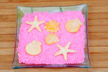 Soaps with shapes of shells and starfish on pink bath salts in a