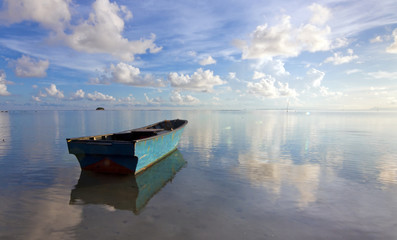 Lonely boat at sea with reflection of blue sky