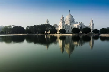 Fotobehang Victoria Memorial, Kolkata, Calcutta, West-Bengalen, India met blauwe lucht en reflectie op water. Een historisch monument van Indiase architectuur, ter herdenking van de 25-jarige regering van koningin Victoria in India. © mitrarudra