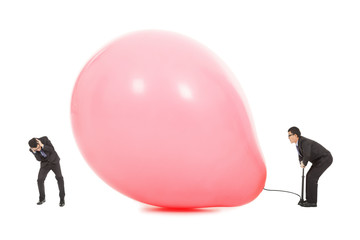 Businessmen scared balloon is inflated to burst