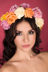 Girl with a wreath of flowers studio shot of a pink background