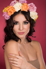 Naklejka premium Girl with a wreath of flowers studio shot of a pink background