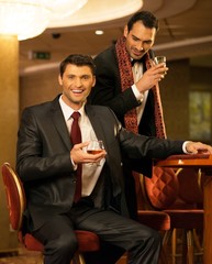 Two young men in suits behind gambling table in casino