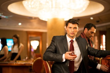 Two young men in suits behind gambling table in casino