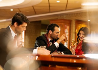 Happy young people behind gambling table with drinks