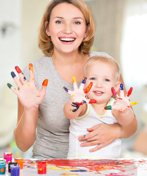 Happy young mother and child with painted hands.