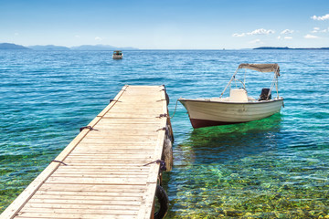 Empty boat standing at wooden pier under bright sunlight