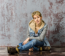 Fototapeta na wymiar girl with short hair wearing jeans and a jacket at the wall
